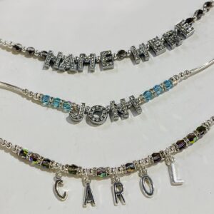 Three necklaces with different letters and a name.